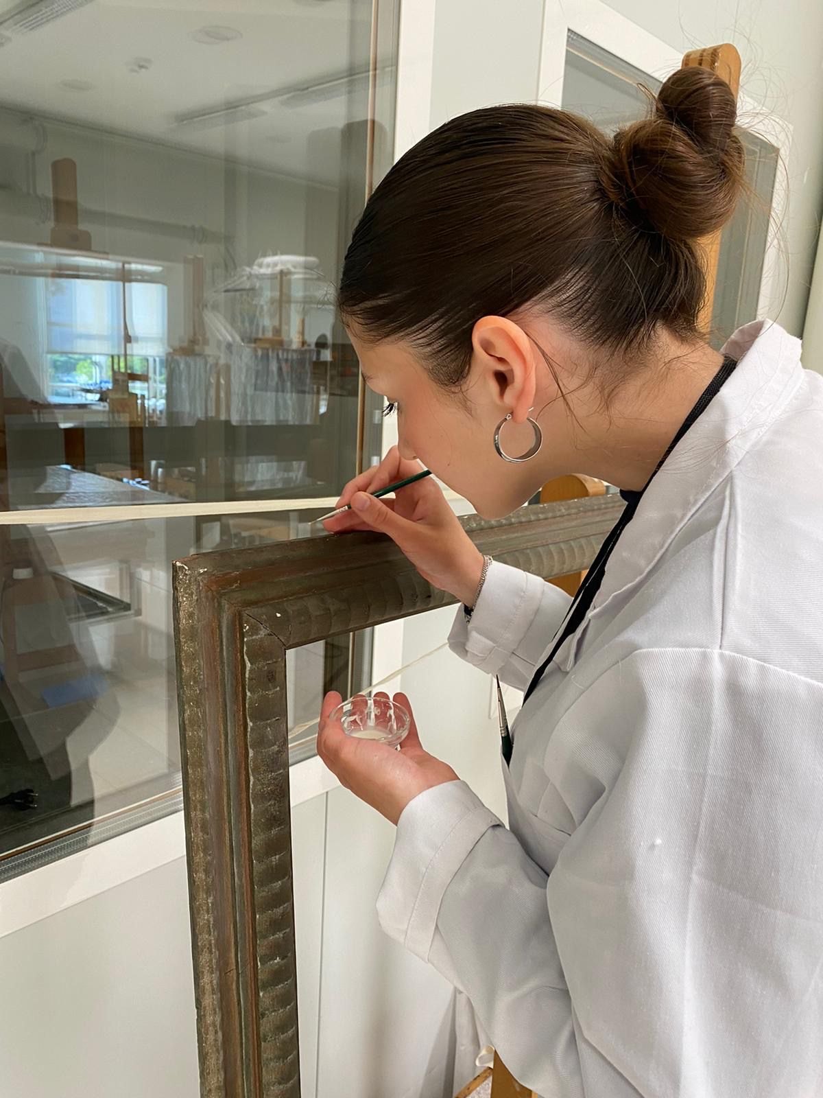 Iris trabajando sobre un marco en el taller